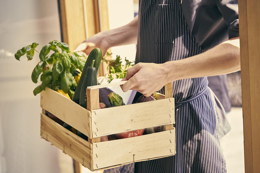 Cropped view of chef carrying crate of vegetables Photograph by Ingolf Hatz