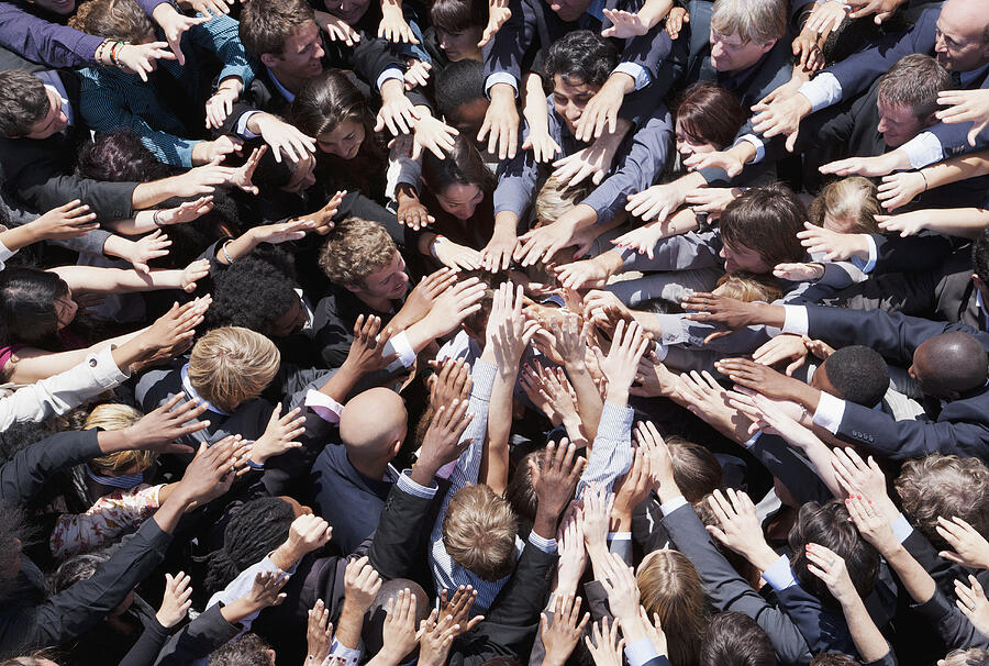Crowd of business people extending hands in huddle Photograph by Martin Barraud