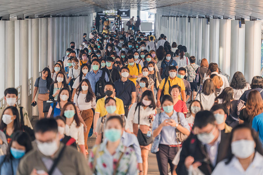 Crowds of Asian people wearing face protection while going to their workplace in Bangkok at morning rush hour Photograph by MR.Cole_Photographer