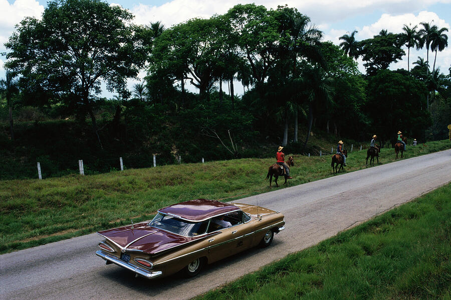 Cuba, horsemen and car on road towards Trinidad Town, elevated view... Photograph by Christopher Pillitz