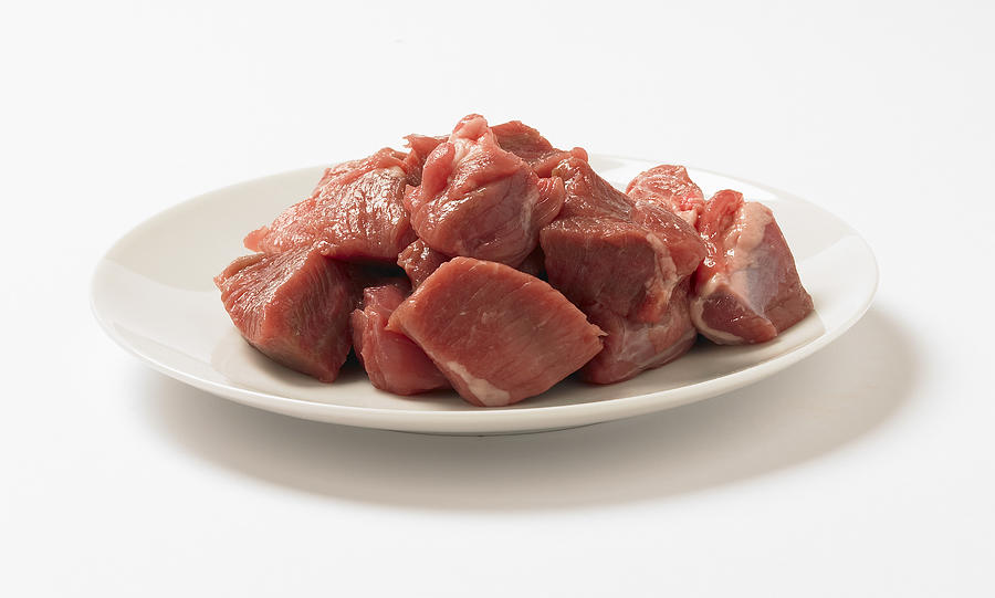 Cubed lamb meat on a plate, studio shot Photograph by Howard Shooter