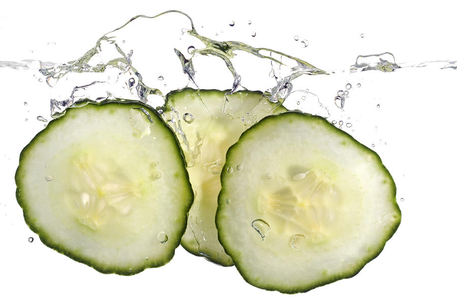 Cucumber slices splashing in water Photograph by Stockcam