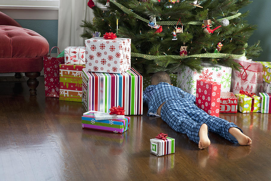 Curious boy digging through presents under tree Photograph by Inti St. Clair