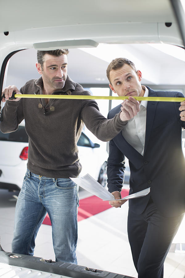 Customer and salesman measuring van interior in car dealership Photograph by Zero Creatives