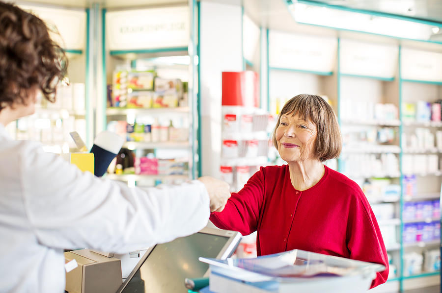 Customer receiving medication from pharmacist Photograph by Alvarez