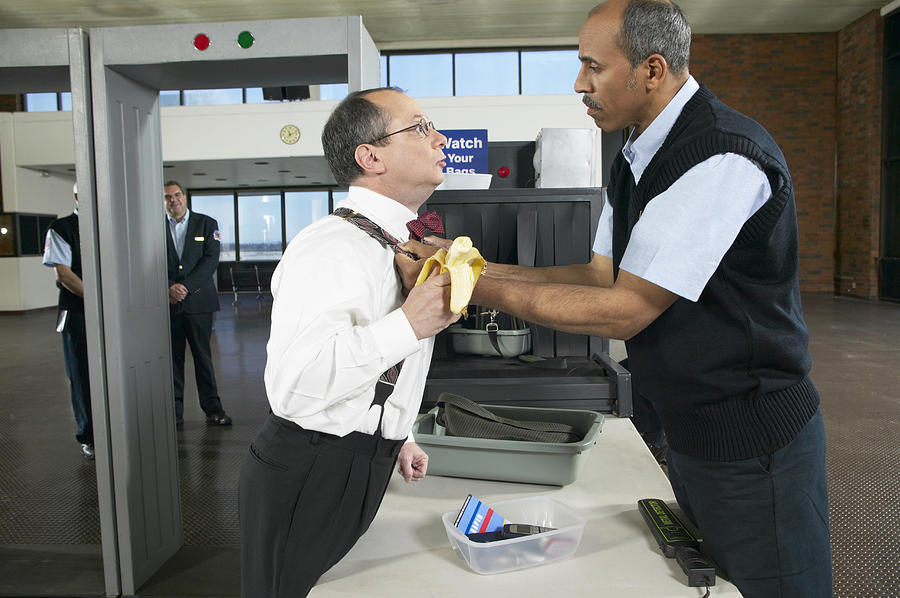 Customs Official Threatening a Man at an Airport Security Checkpoint Photograph by Digital Vision.
