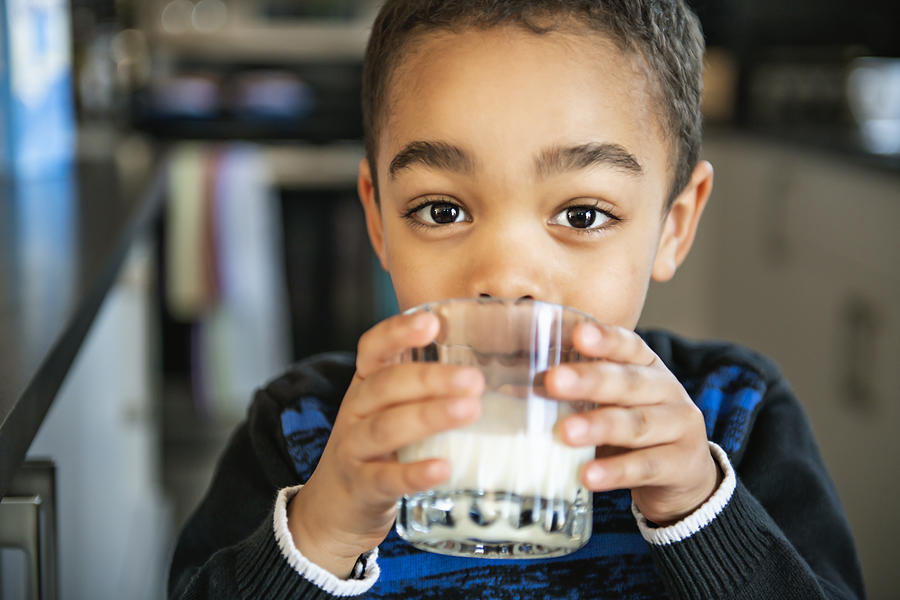 Cute African American boy drinking milk at home Photograph by LSOphoto