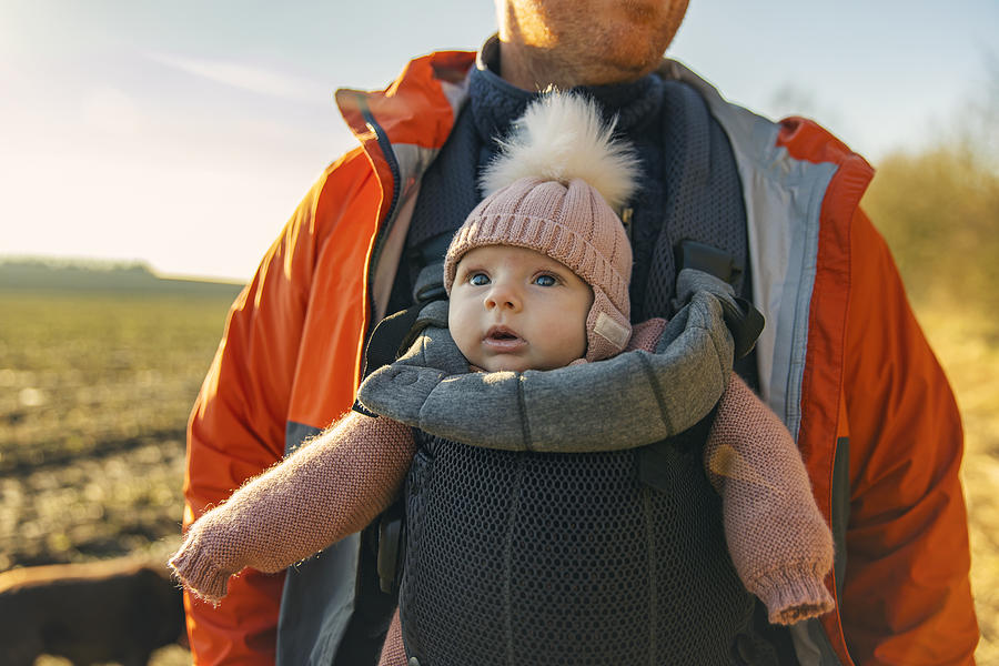 Cute baby girl being carried by her father in a baby carrier whilst out for a walk Photograph by Justin Paget