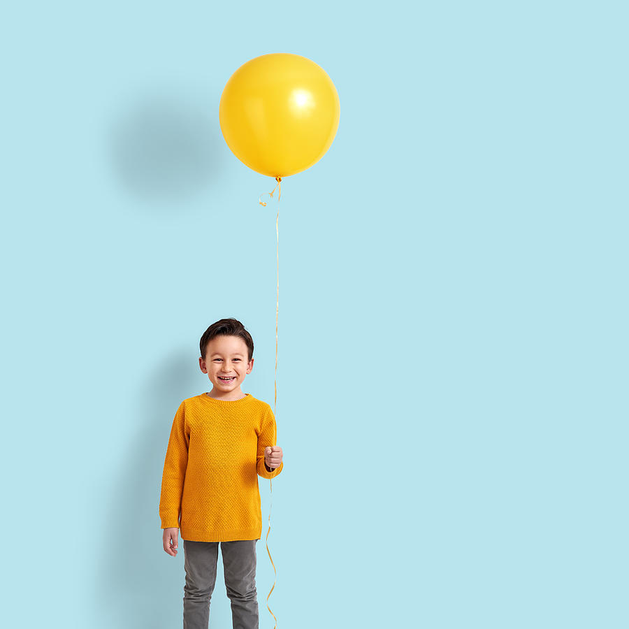 Cute child holding a yellow balloon Photograph by Pinstock