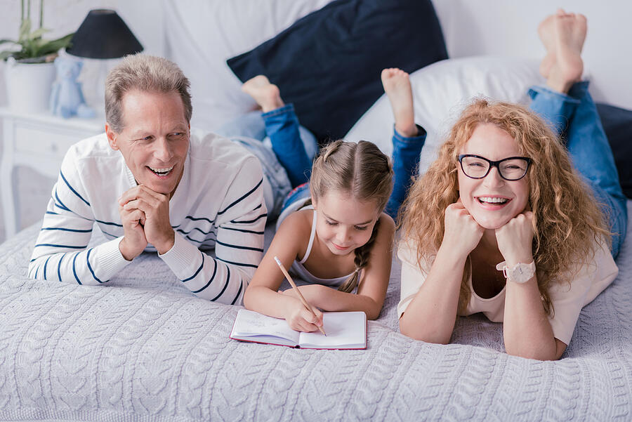 Cute girl drawing and having fun with her grandparents Photograph by Yacobchuk