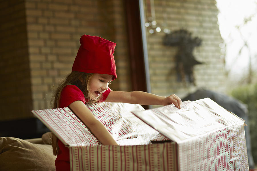 Cute girl opening big christmas present Photograph by Klaus Vedfelt