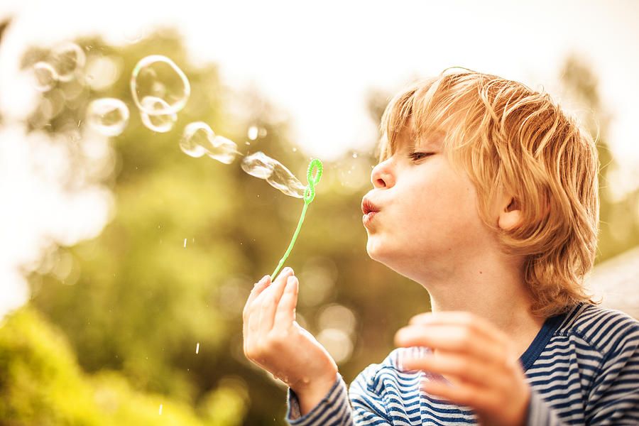 Cute little boy outdoors blowing bubbles Photograph by Knape