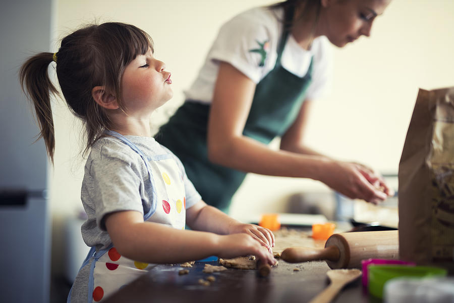 Cute little girl baking at home with mom Photograph by ArtistGNDphotography