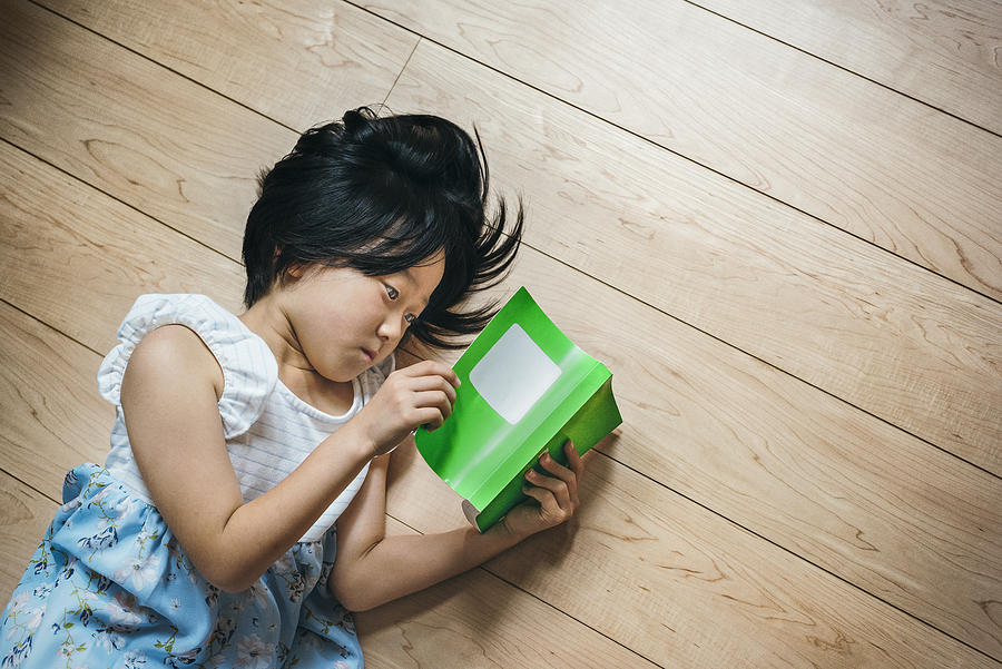 Cute little girl reading book on the floor Photograph by EujarimPhotography