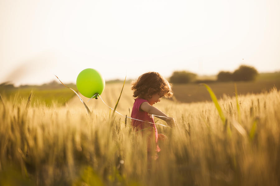 Cute little girl with balloons at field Photograph by Vesnaandjic