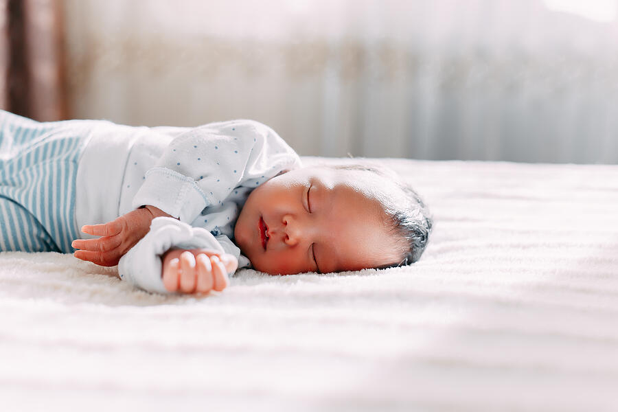 Cute newborn brunete baby sleeps lying on soft plaid Photograph by Nestea06