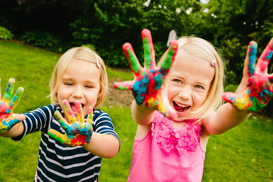 Cute sisters having fun with finger paint Photograph by Wundervisuals