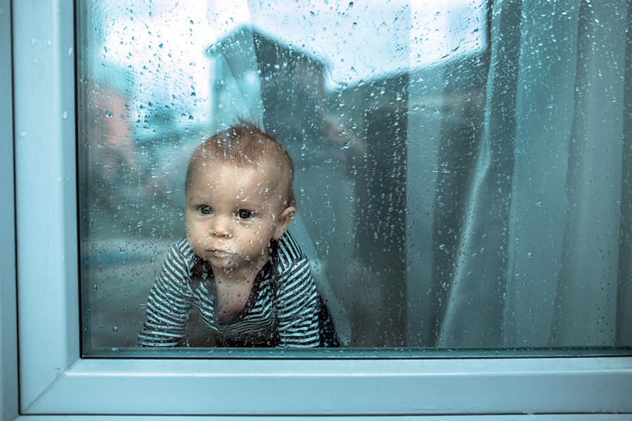 Cute toddler boy, staying at home behind the glass doors or window, watching outsiden Photograph by Tatyana Tomsickova Photography