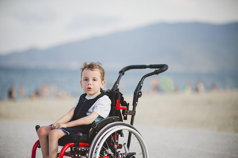 Cute young boy on the wheelchair by the sea Photograph by Dmphoto