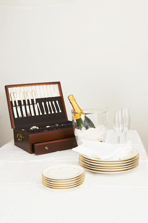 Cutlery box with a champagne bottle and tableware on a dining table Photograph by Glowimages