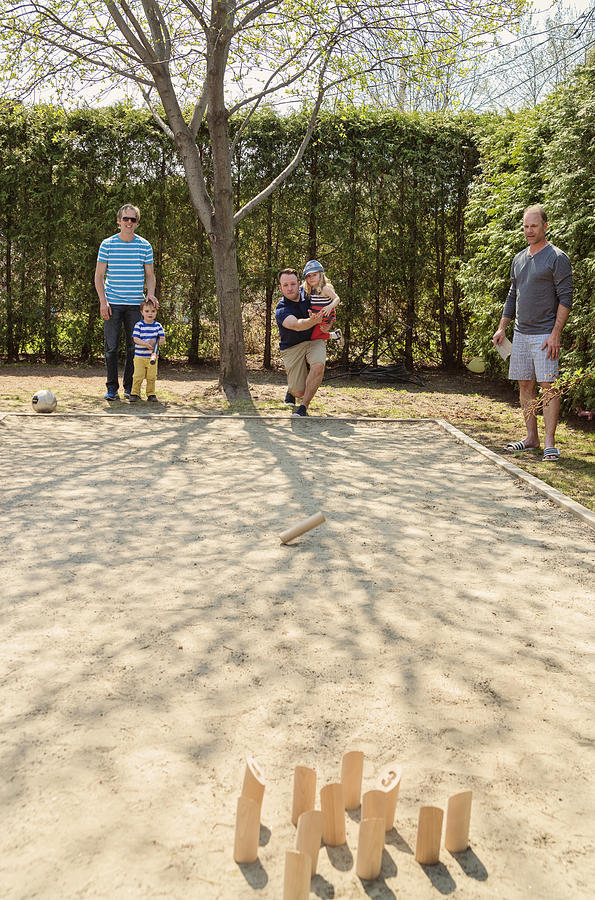 Dads and little children playing Molkky, wood skittles game outdoors. Photograph by Martinedoucet