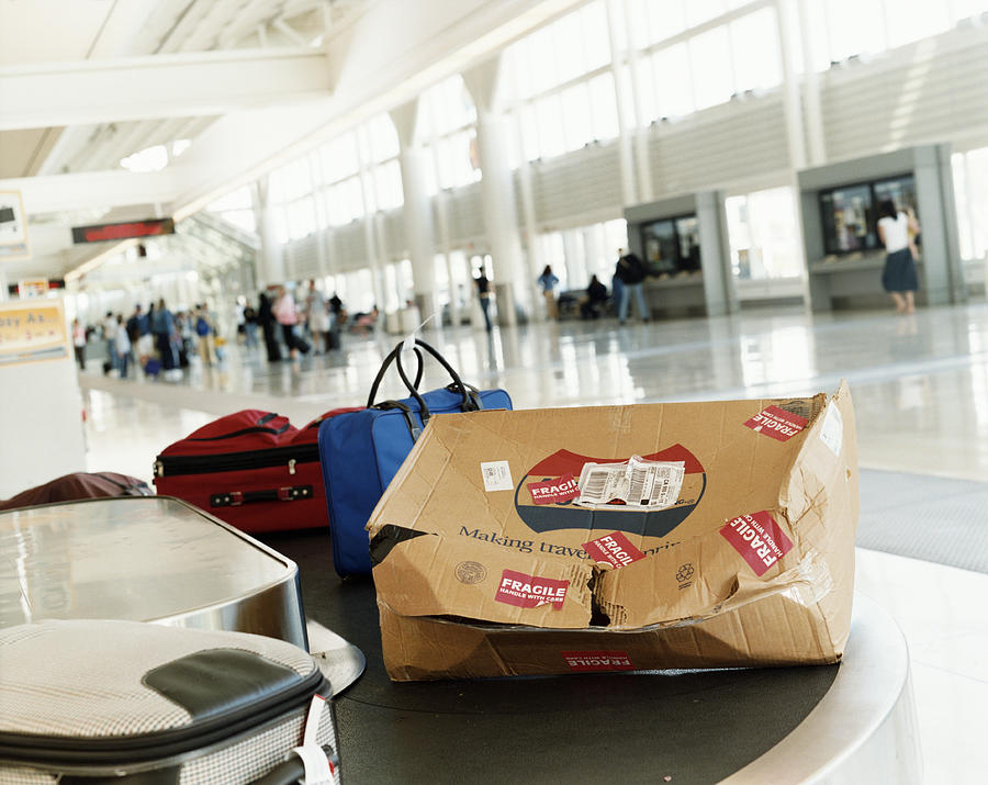 Damaged Package on a Airport Baggage Conveyor Belt Photograph by Digital Vision.