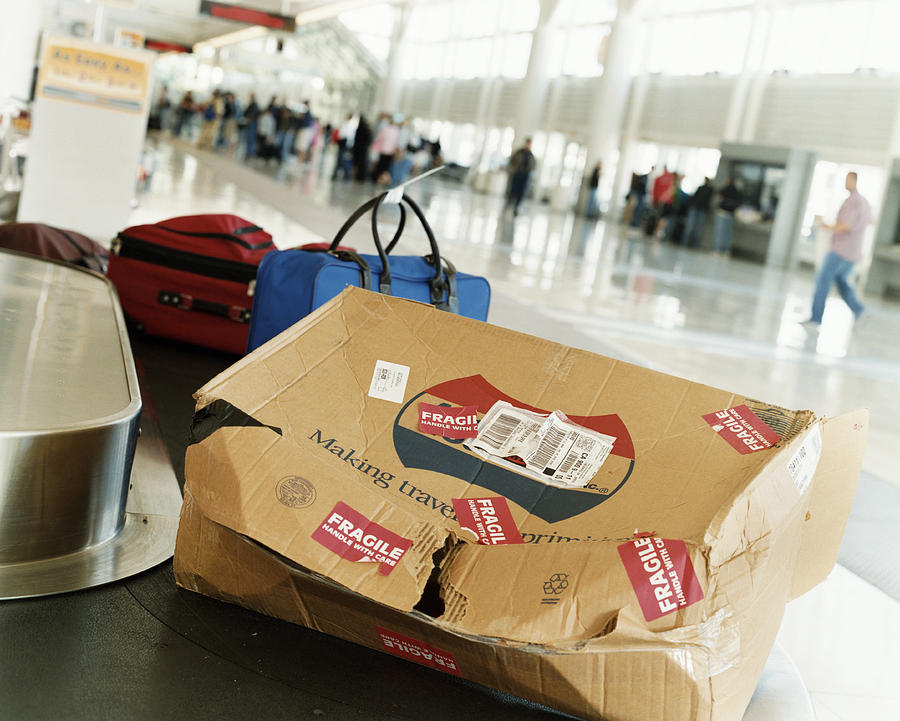 Damaged Package on an Airport Baggage Collection Conveyor Belt Photograph by Digital Vision.