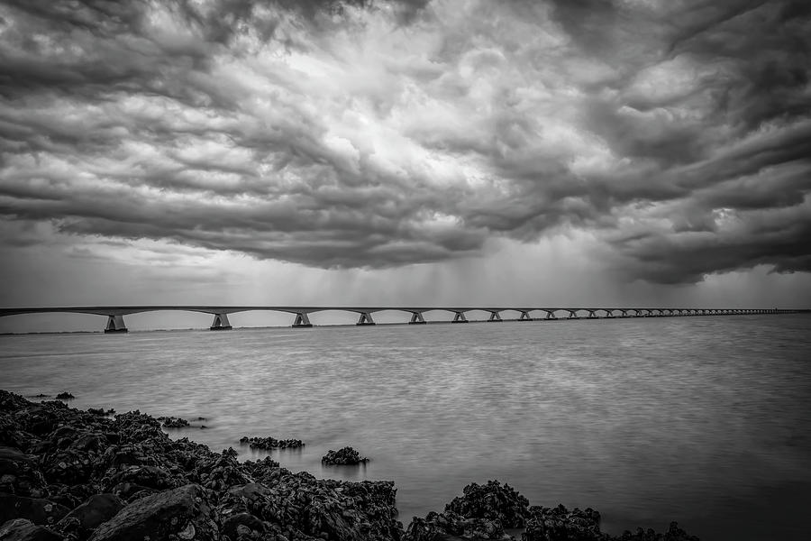 Dark clouds Zeeland Bridge in black and white Photograph by Marjolein Van Middelkoop