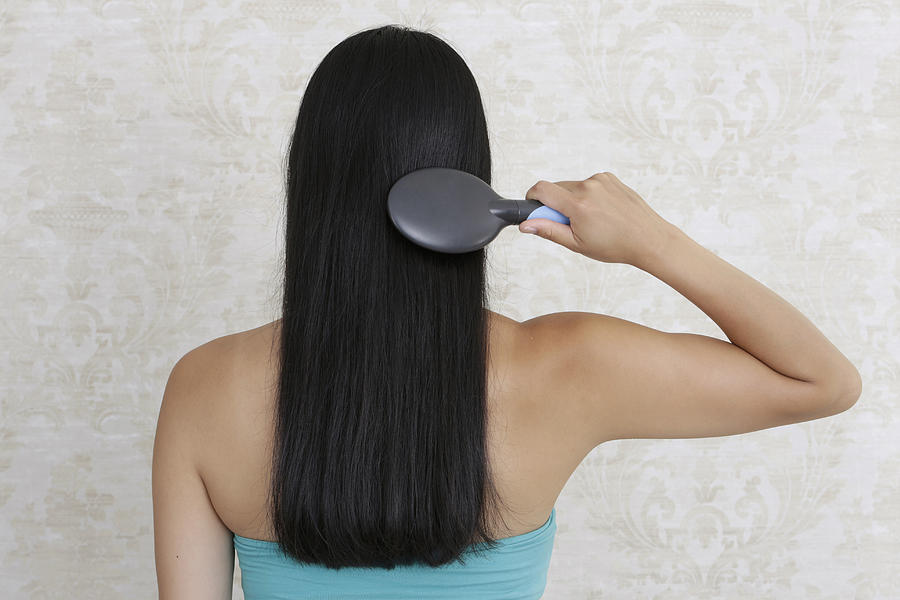 Dark-haired woman brushing her hair, rear view Photograph by Sarah Kastner / STOCK4B-RF