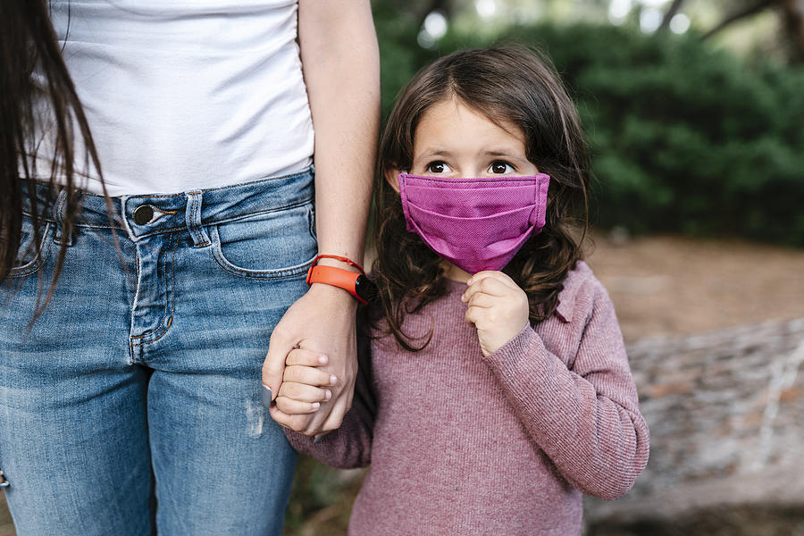 Daughter wearing protective mask and holding hand of her mother Photograph by Westend61