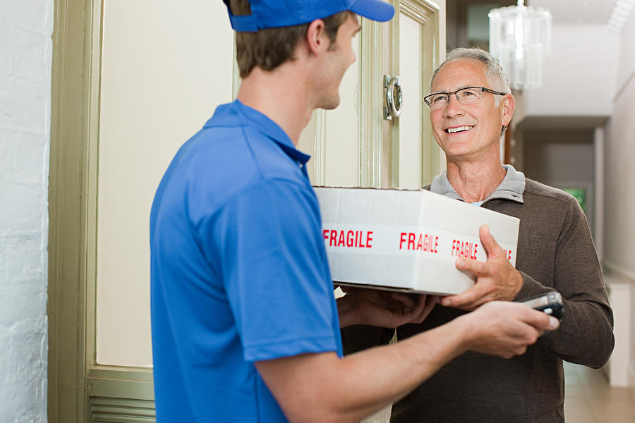 Delivery man delivering parcel Photograph by Image Source