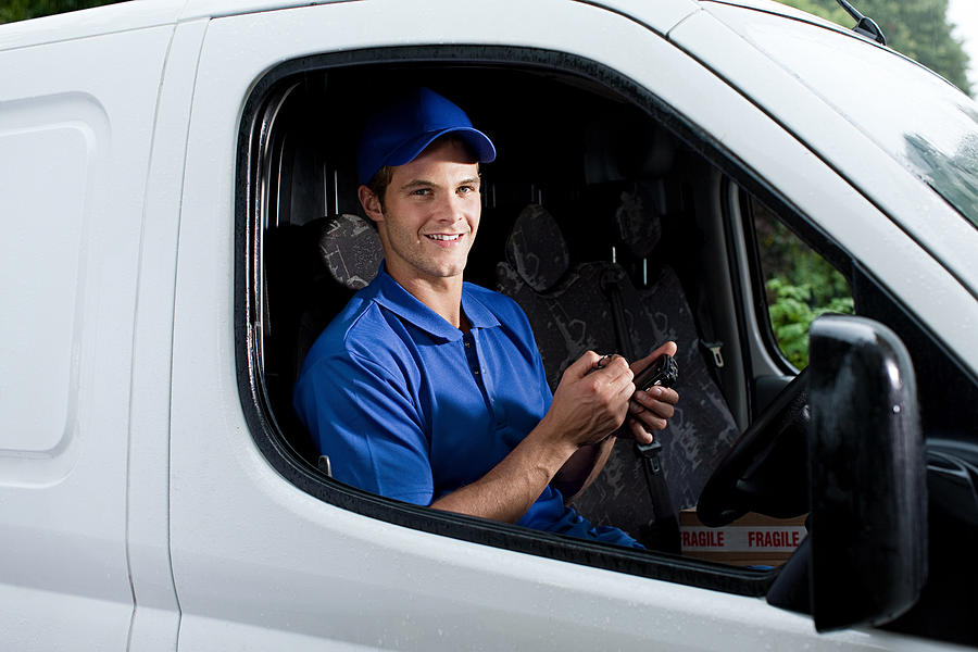 Delivery man in van with handheld computer Photograph by Image Source