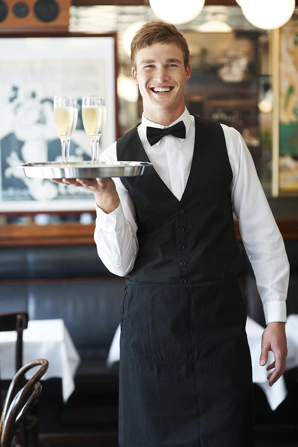 Denmark, Aarhus, Portrait of waiter holding champagne flutes on tray Photograph by Tetra Images - Yuri Arcurs