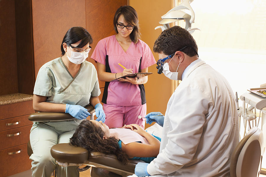 Dentist and hygienists examining patient Photograph by Kingfisher Productions