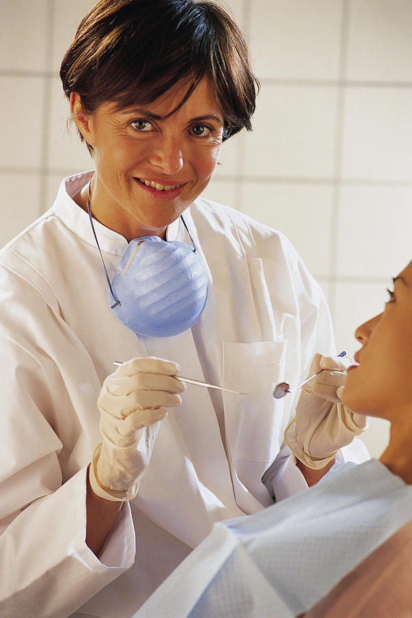 Dentist or dental hygienist with patient Photograph by Comstock