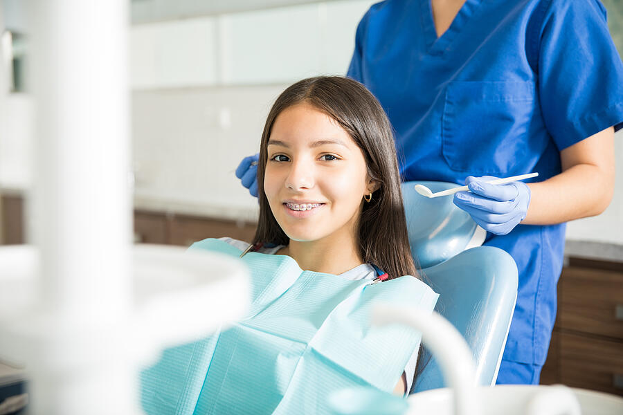 Dentist Standing Behind Smiling Teenage Girl With Braces In Clinic Photograph by Antonio_Diaz