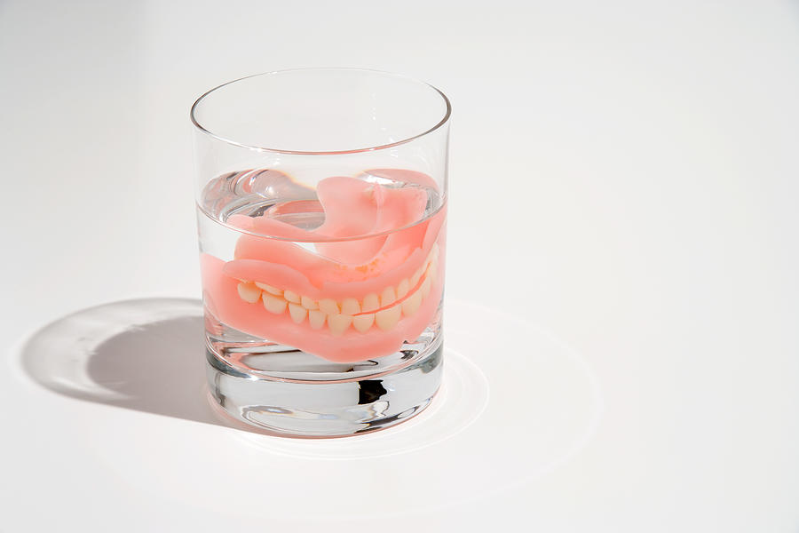 Dentures in a glass of water Photograph by Image Source