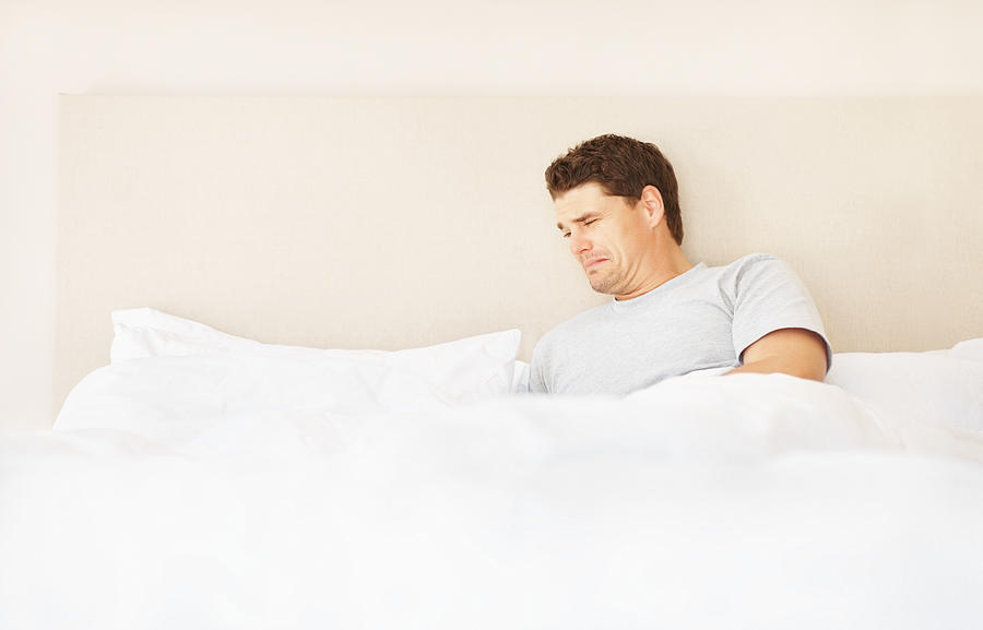 Depressed man looking on empty side of bed Photograph by GlobalStock