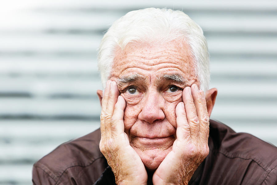 Despairing old man, head in hands, looks at camera Photograph by RapidEye