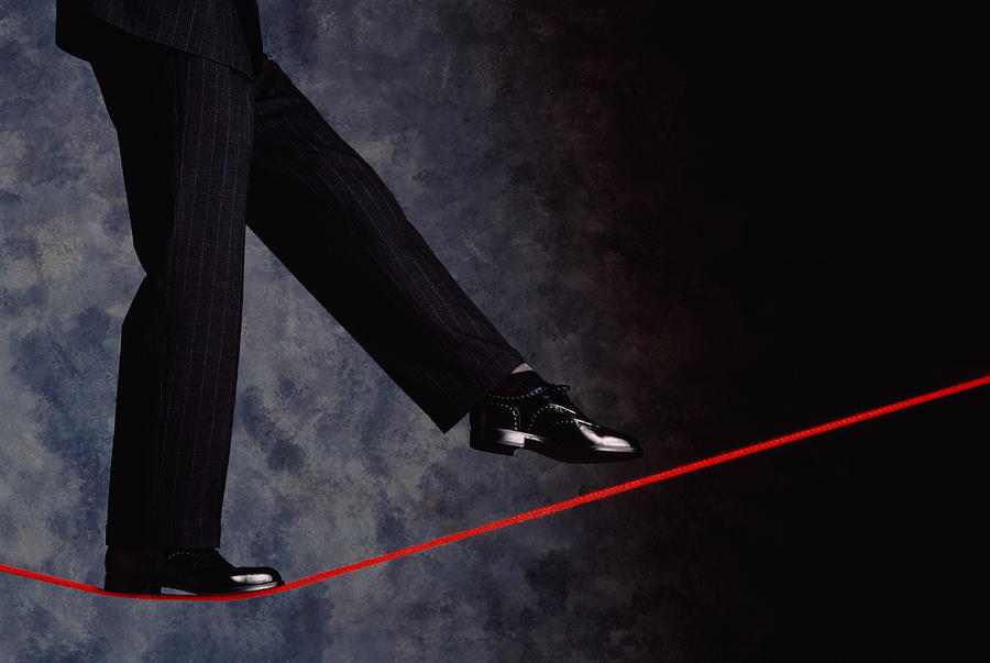 Detail of mans legs in business suit on tighrope,grey background Photograph by Ray Massey