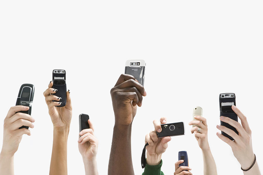 Detail of people with raised hands and holding mobile phones Photograph by Antenna