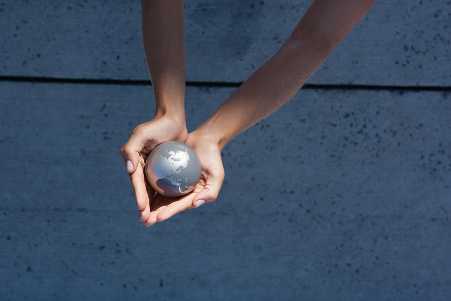 Detailed View of hands holding globe outdoors Photograph by Martin Barraud