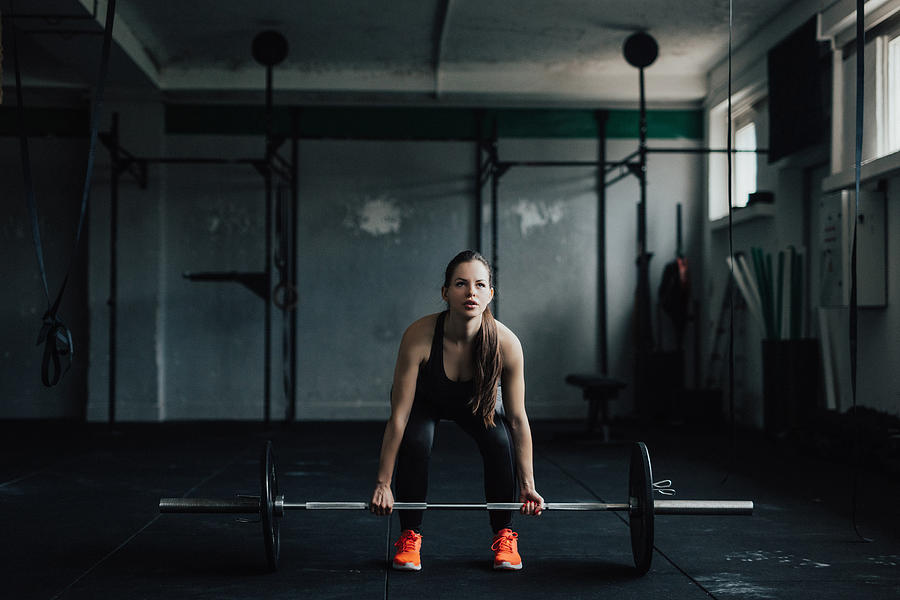 Determined young woman doing deadlift in the gym Photograph by Anchiy