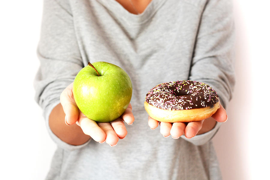 Dieting concept with woman choosing between healthy fruits and donut Photograph by Adrian825