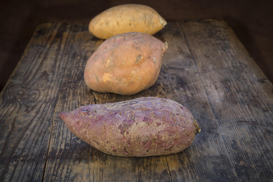 Different Sweet Potatoes On Dark Wood Photograph by Larissa Veronesi