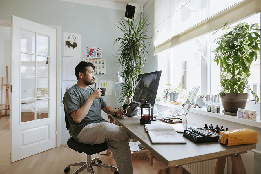 Digital artist contemplates during coffee break in his home office Photograph by Visualspace