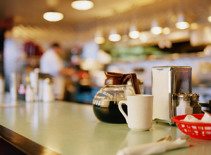 Diner counter top with coffee pot and cup next to napkin dispenser Photograph by Terry Vine