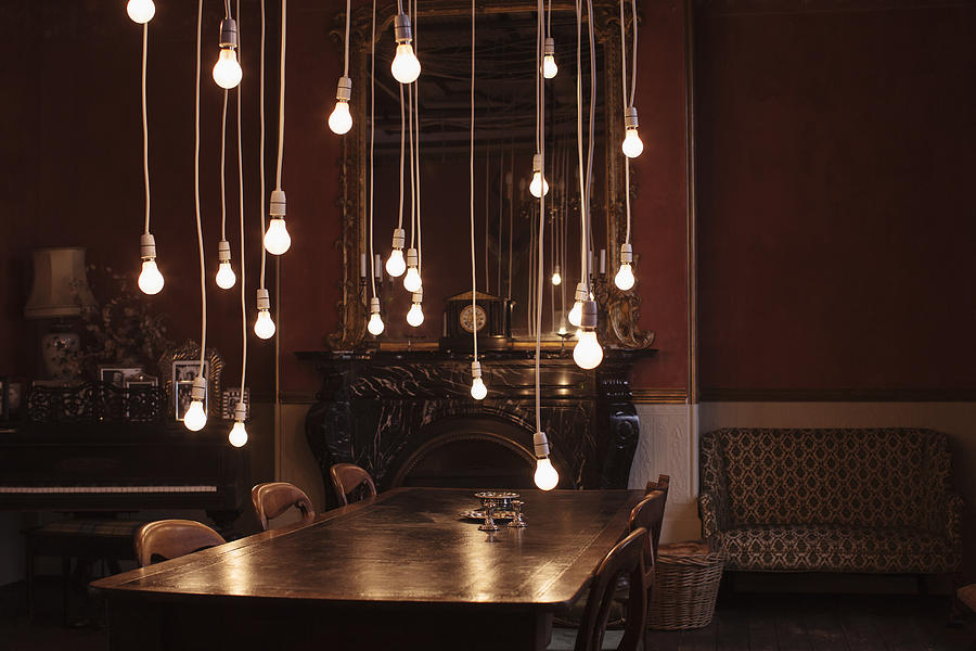Dining room with hanging lightbulbs Photograph by Anthony Harvie