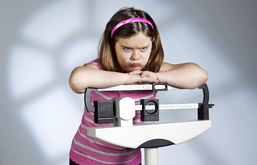 Disappointed overweight girl on scales Photograph by Peter Dazeley
