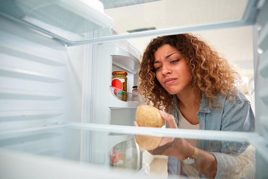 Disappointed Woman Looking Inside Refrigerator Empty Except For Potato On Shelf Photograph by Monkeybusinessimages